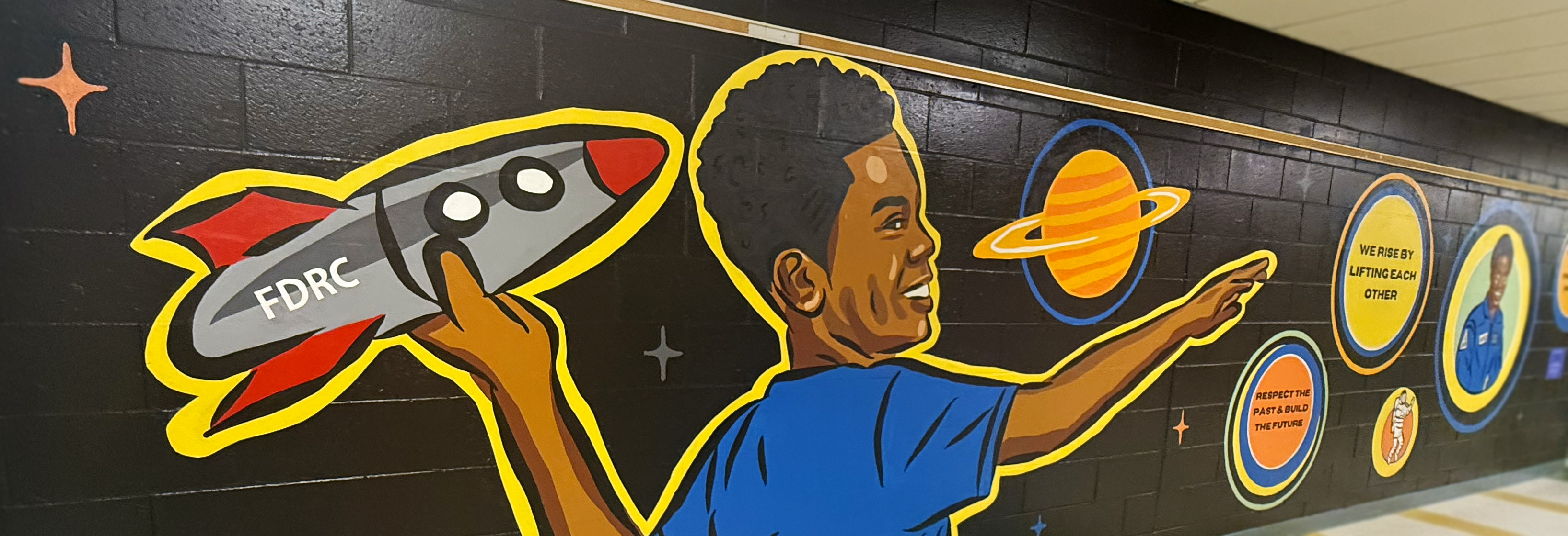 Colorful school hallway mural showing a child holding a rocket and reaching toward planets and inspiring messages.